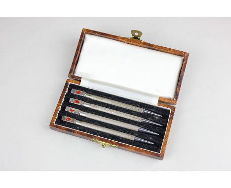 A set of four sterling silver mechanical bridge pencils, each with reeded bodies, the tops decorated with the four suits (a/f