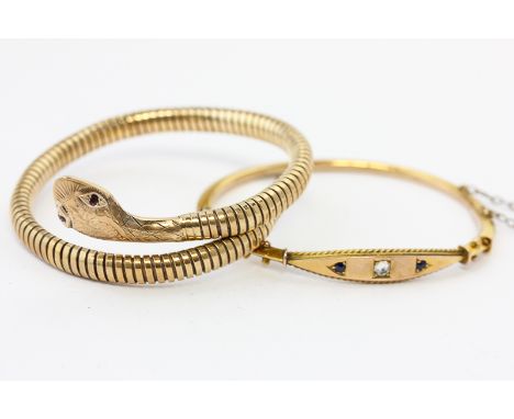 A 9ct gold serpent bangle the sprung coils and ruby eyes; and a 9ct gold and sapphire bangle