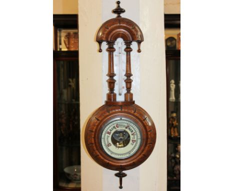 An early 20th century aneroid wheel barometer with thermometer in carved oak case, 57cm