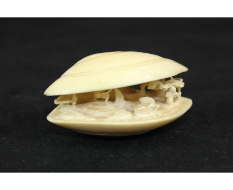 An early 20th century Japanese clam shell form netsuke carved with an interior agricultural scene, 5.5cm wide