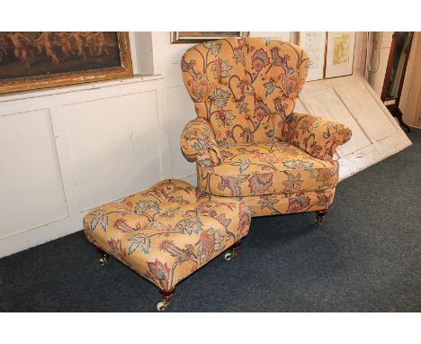 A modern button back armchair with loose cushion and stool, in floral upholstery, on turned feet and castors