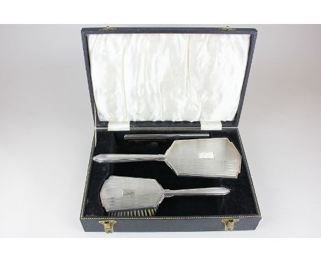 An Art Deco style sterling silver backed dressing table set of hair brush, hand mirror and comb in fitted case