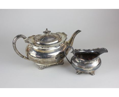 A George V silver teapot, oval shape with raised scroll border, and a matching cream jug, Robert & William Sorley, Glasgow 19