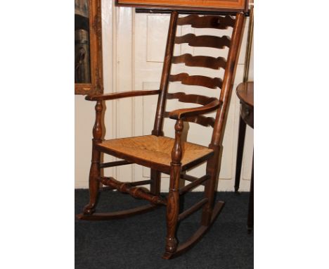An oak ladder back rocking chair with rush seat and turned stretcher