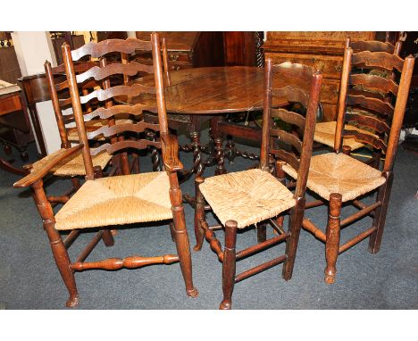 A set of seven oak ladder back dining chairs including one carver, with rush seats, on turned legs with front pad feet