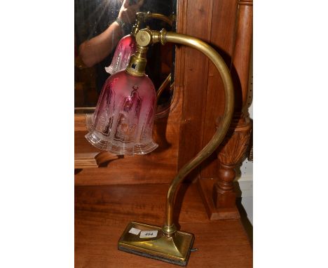 An early 20th century table lamp, cranberry flashed shade, brass scroll arm, rectangular base