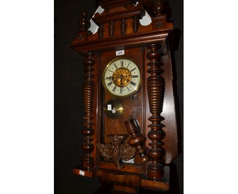 A late 19th century walnut Vienna wall clock, the white ivorine dial with Roman numerals, twin winding holes, architectural p