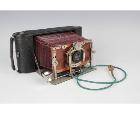 An early 20th century folding camera with burgundy leather bellows and silvered and gilt brass mounted 'Unicum' shutter, the 