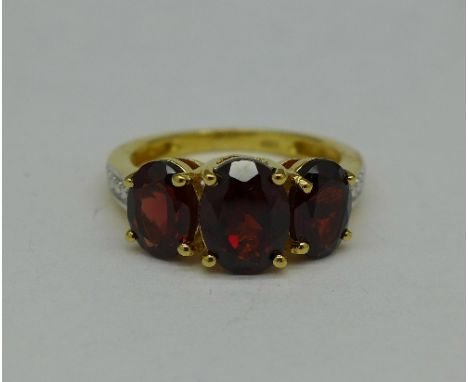 A silver gilt and garnet trilogy ring, K