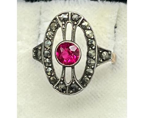 Gold and silver art deco ring set with a single round cut ruby surrounded by marcasite stones. [Ring- no hallmarks] [Ring siz