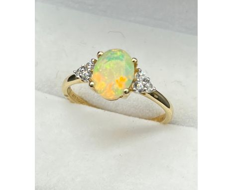 10ct yellow gold ladies ring set with an Oval cut opalescent style centre stone off set by three white spinel stones two each