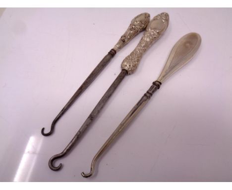 Three silver handled button hooks.