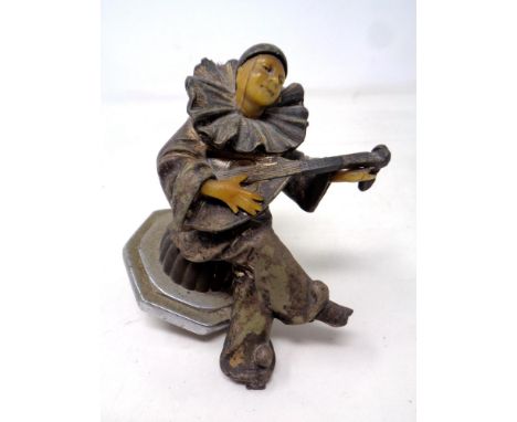 A vintage metal car mascot modelled as a dancing figure playing a lute