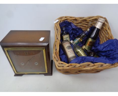 A 1930's oak Smiths Enfield 8-day mantel clock together with wicker basket of alcohol miniatures 