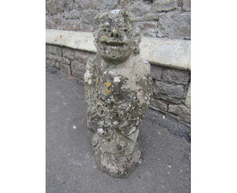 A weathered stone garden figure of a standing leprechaun with defined features, holding a harp with winged figure head mount,