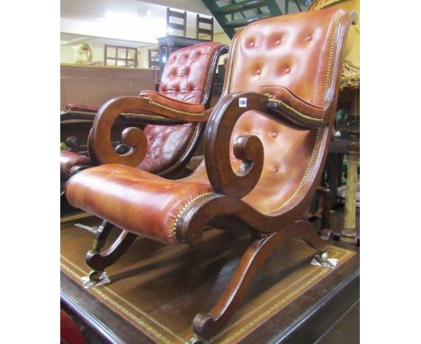A Regency mahogany X framed library chair with scrolled arms, upholstered in mid-tan brown leather with button back and brass