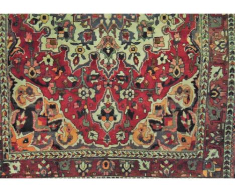 A heavy wool carpet in the Persian style, with central medallion upon a white field, further red borders and set within trail