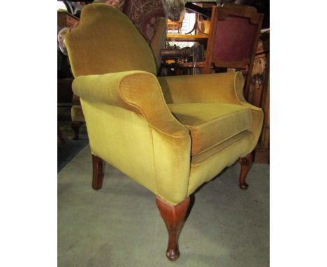 A Queen Anne style pale yellow ground upholstered armchair with shield shaped back, swept arms, loose seat cushion and squat 