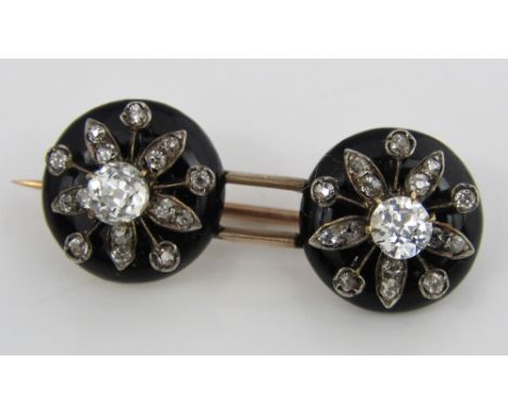 A Victorian black enamel mourning brooch with diamond set flower head decoration, in unmarked gold and silver, two largest di