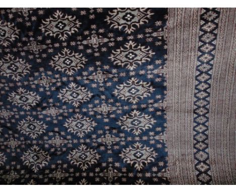 An eastern wool carpet with ink black field, with multi geometric panels, set within wide running borders, 380 x 280cm