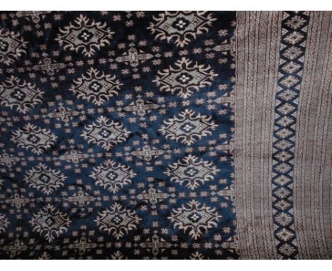 An eastern wool carpet with ink black field, with multi geometric panels, set within wide running borders, 380 x 280cm