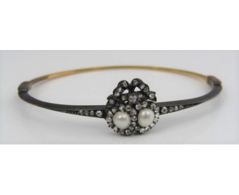 A diamond and pearl hinged sweetheart bangle with pearl set double hearts and bow surmount, in unmarked gold and silver, in o