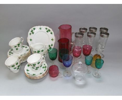 A mixed collection of coloured glassware to include various coloured wine glasses and cranberry jugs; together with a further