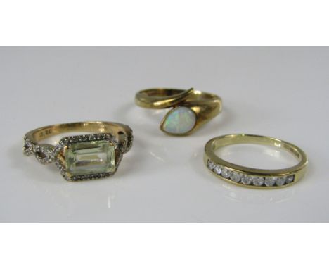 Three contemporary 9ct rings; a pear cut opal crossover ring, a channel set diamond example and a further diamond set example