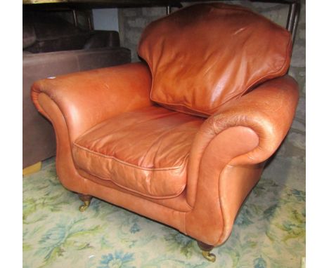A contemporary light tan leather upholstered easy chair with swept rolled and waisted outline and loose squab cushions, raise