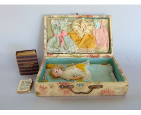 Interesting textile lined case, the hinged lid enclosing a porcelain doll with clothes and a scale book of affections token, 