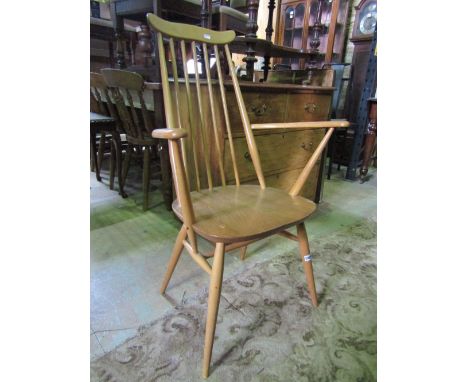 An Ercol light elm and beechwood high stick back open elbow chair with cow horn cresting rail, raised on splayed turned taper