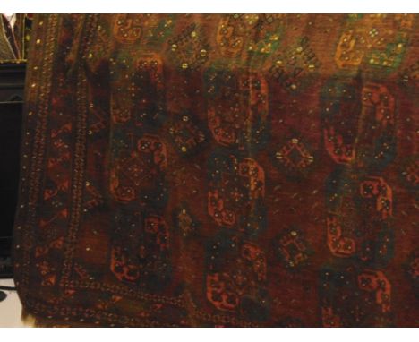 A large old Afghan wool carpet, with multi medallion panels of hexagonal form upon a red ground field, within alternating geo