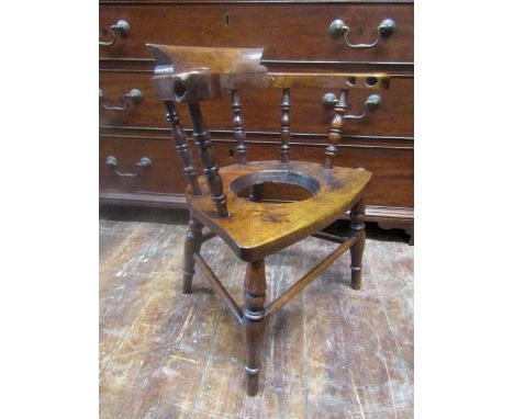 A 19th century Windsor child's elbow chair to a smokers bow design, in mixed woods, the seat to accommodate a commode