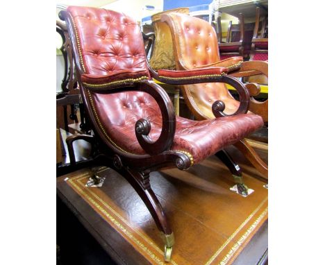 A William IV mahogany X framed library chair with scrolled arms and maroon coloured button back leather finish and brass stud