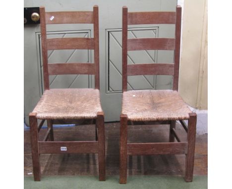 A pair of Heal's simple ladder back side chairs in fumed oak with rush seats