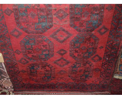 An Afghan red wool carpet with multi medallion centre upon a deep red field, within alternating borders, 210 x 135cm 