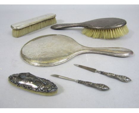 A collection of silver dressing items to include a mirror, two brushes, a blusher and two manicure tools (6)