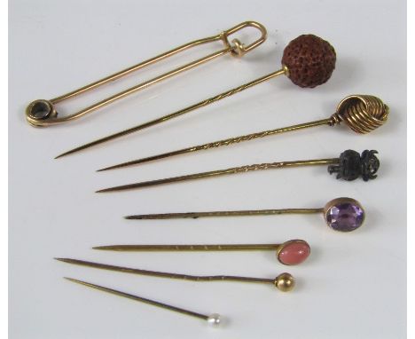 A collection of gold and yellow metal stick pins to include an imp pin set with rose cut diamond eyes, a faceted amethyst exa