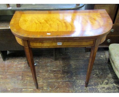 A Georgian mahogany satin-wood D end foldover top card table, crossbanded in rosewood and raised on square tapered legs, with