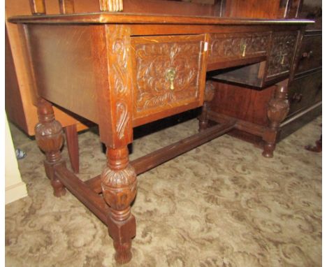 A late Victorian oak kneehole dressing table/desk fitted with an arrangement of three frieze drawers with carved C scroll and