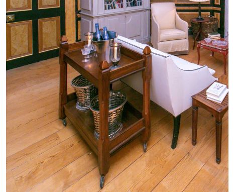An early 20th century Arts & Crafts design oak two tiered buffet or drinks trolley, with stop chamfered columns on swivel cas