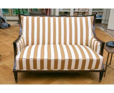 A contemporary curved backed mahogany two seater sofa, with broad striped stuff over fabric on square tapering architectural 