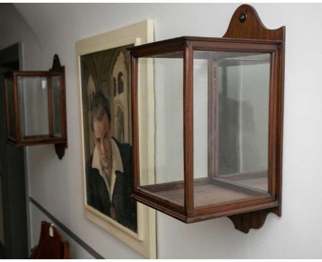 A pair of late Victorian mahogany glazed storm lamp holders or wall lanterns, with shaped backboards. (2) 26cm wide x 26cm de