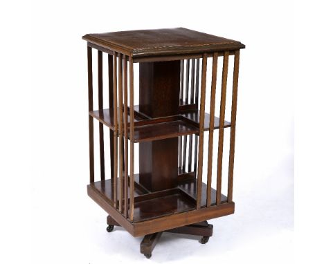 AN EDWARDIAN MAHOGANY ROTATING BOOKCASE on a wooden stand with decorative satinwood crossbanding to the top, 47cm square x 84