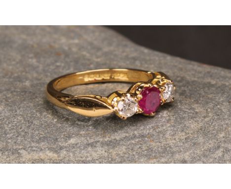 An 18ct gold three stone diamond and ruby ring, diamonds 0.34ct, ruby 0.58ct, size M