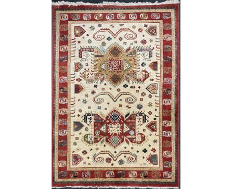 A Kabir rug/carpet, two principle shaped medallions within cream field, rustet red cream and green multi layer border, approx