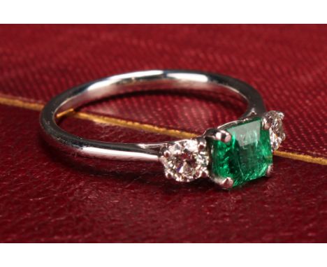 An 18ct white gold diamond and emerald three stone ring, emerald 0.66ct, diamonds 0.37ct, size L