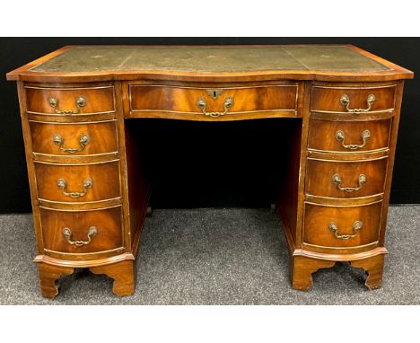 A George III revival serpentine front mahogany pedestal desk, green leather writing surface, four graduated short drawers to 