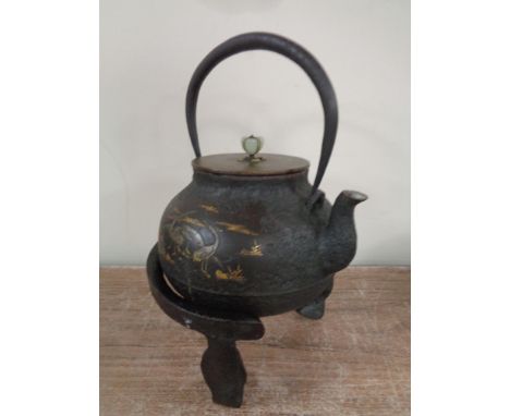 A Japanese cast iron teapot with gold inlay depicting stalks, on stand  CONDITION REPORT: In pitted but otherwise good condit
