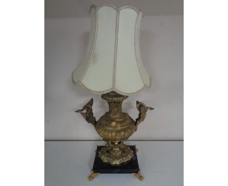 An early twentieth century ornate brass table lamp depicting swans in flight above cherubs on black marble base with shade 